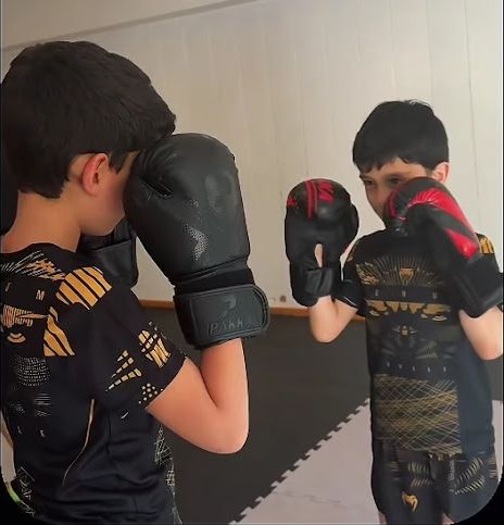 Zwei Kinder trainieren mit Boxhandschuhen gegeneinander
